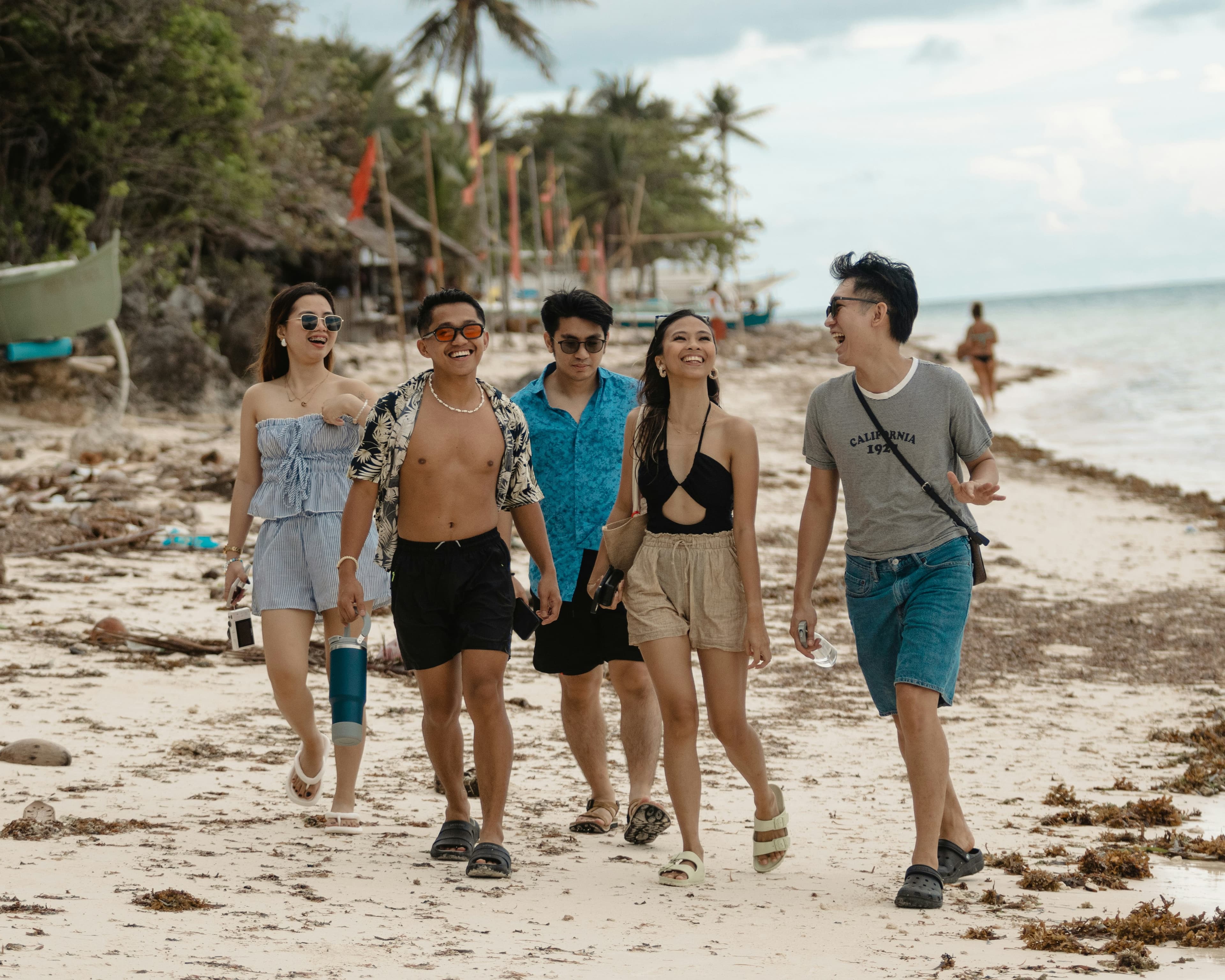Groupe de voyageurs marchant et riant sur une plage tropicale